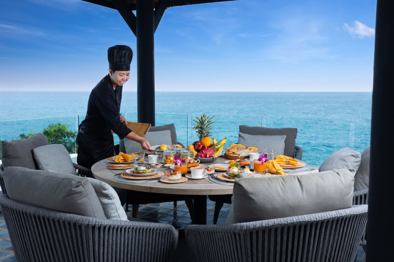 Chef setting up a table for a meal with an ocean view at a villa in Phuket. 