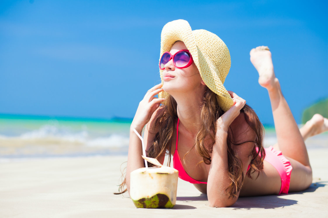 lady in the beach with a coconut drink