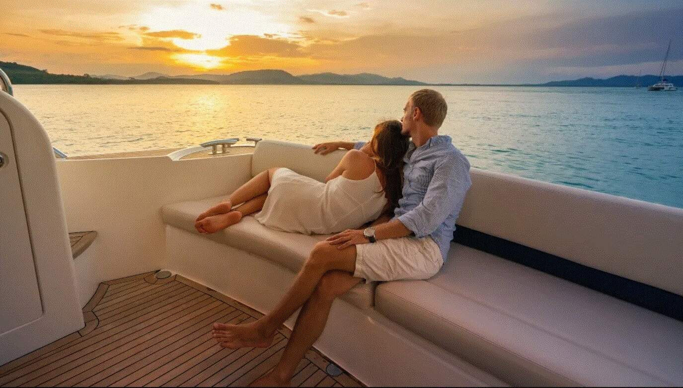 A couple on a yacht charter beneath the sunset